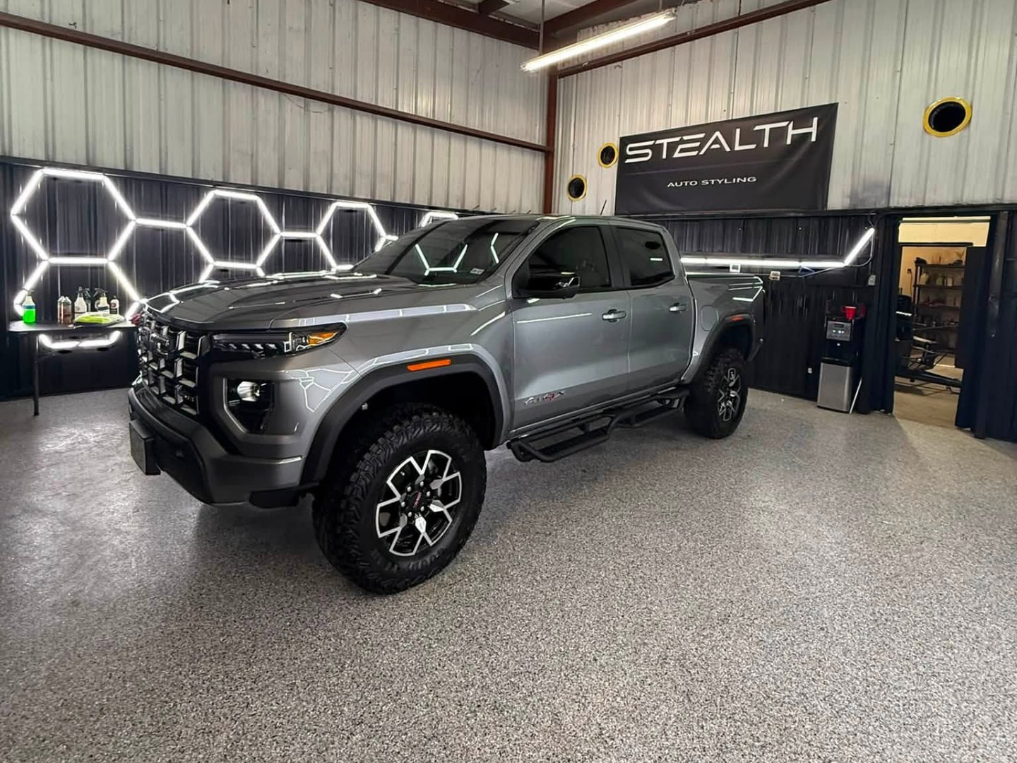Gray GMC Canyon AT4X gleaming on the epoxy floor of the detailing bay