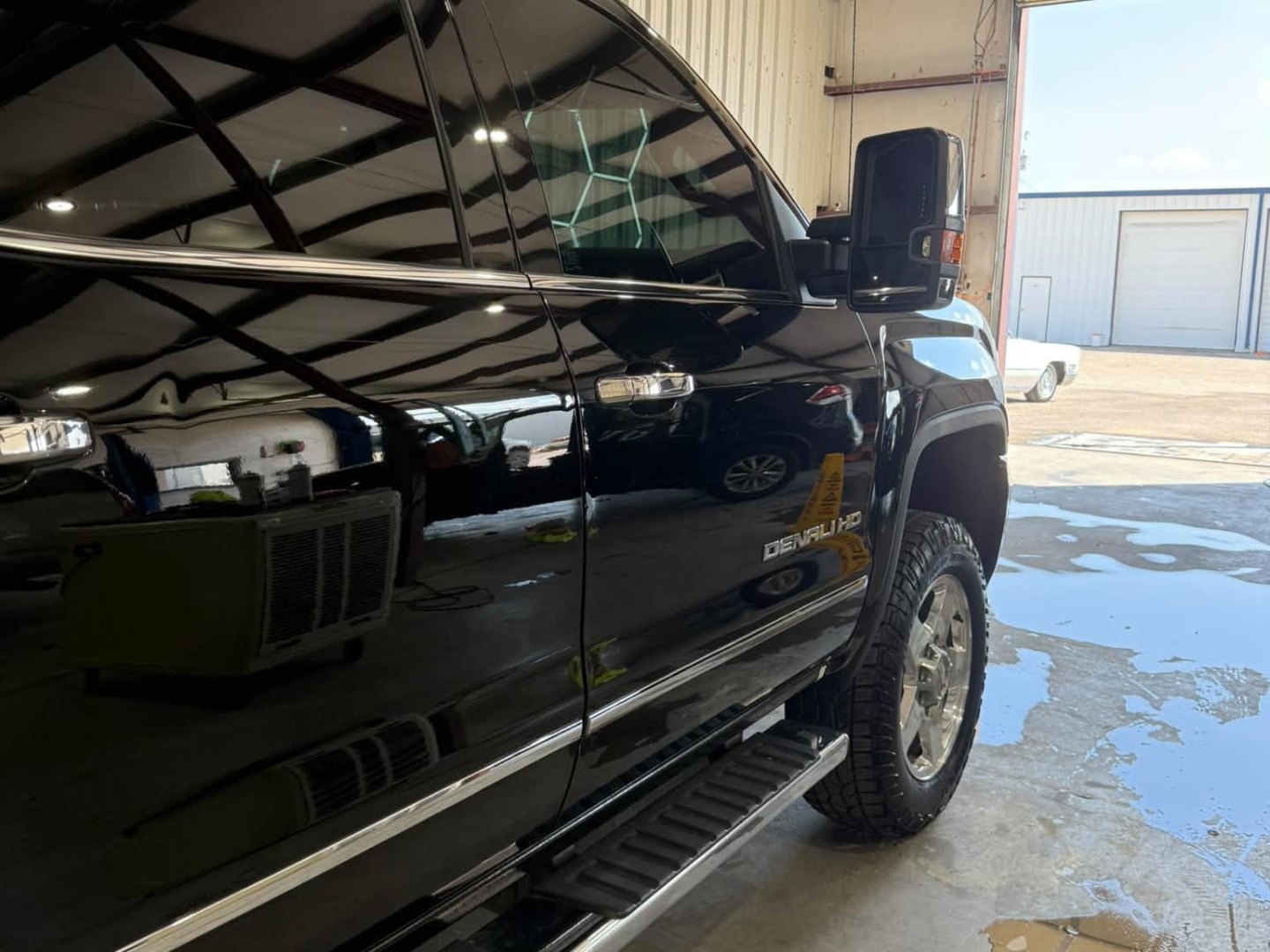 Glossy black GMC Denali HD reflecting the shop lights after detailing