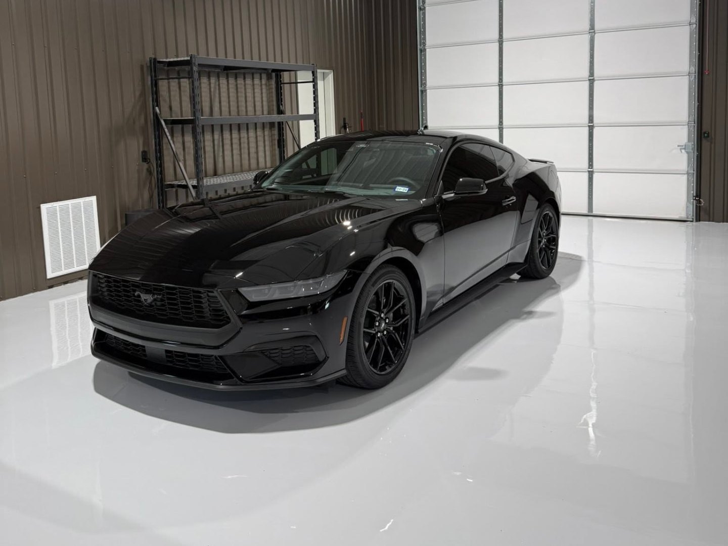 Black Ford Mustang with a deep mirror-gloss finish in a bright detailing bay